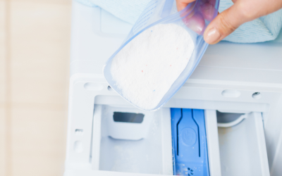 Scoop of laundry detergent being added to washing machine, illustrating oversoaping issue discussed in blog about laundry practices.